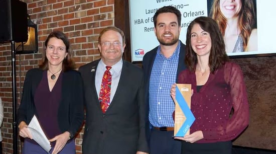 Two women, two men smiling, woman holding award