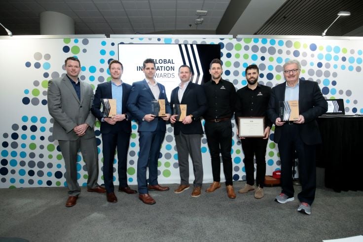 Group of men standing next to each other holding award plaques