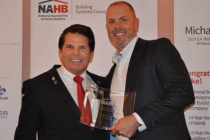 Two men holding award, smiling